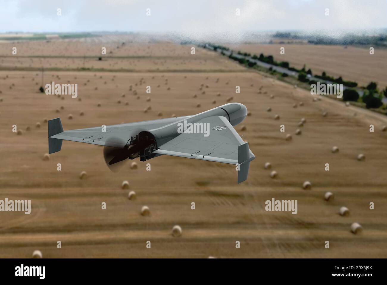 Military kamikaze drone flies over fields with hay countries, attack of unmanned aerial vehicles, war in Ukraine. Stock Photo