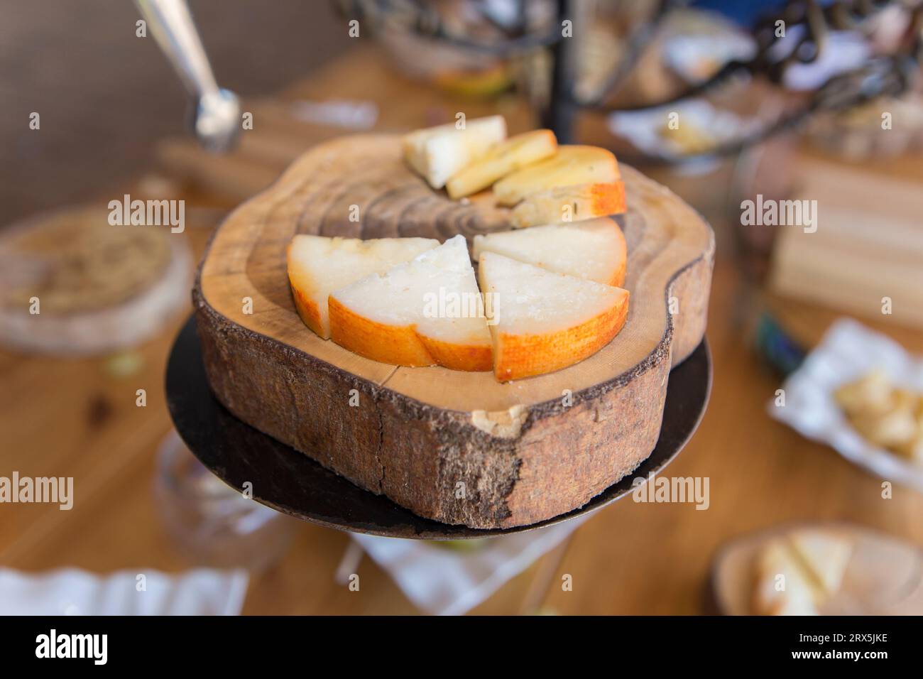 Half-cured smoked paprika cheese slices displayed over tree bark tray. Closeup Stock Photo