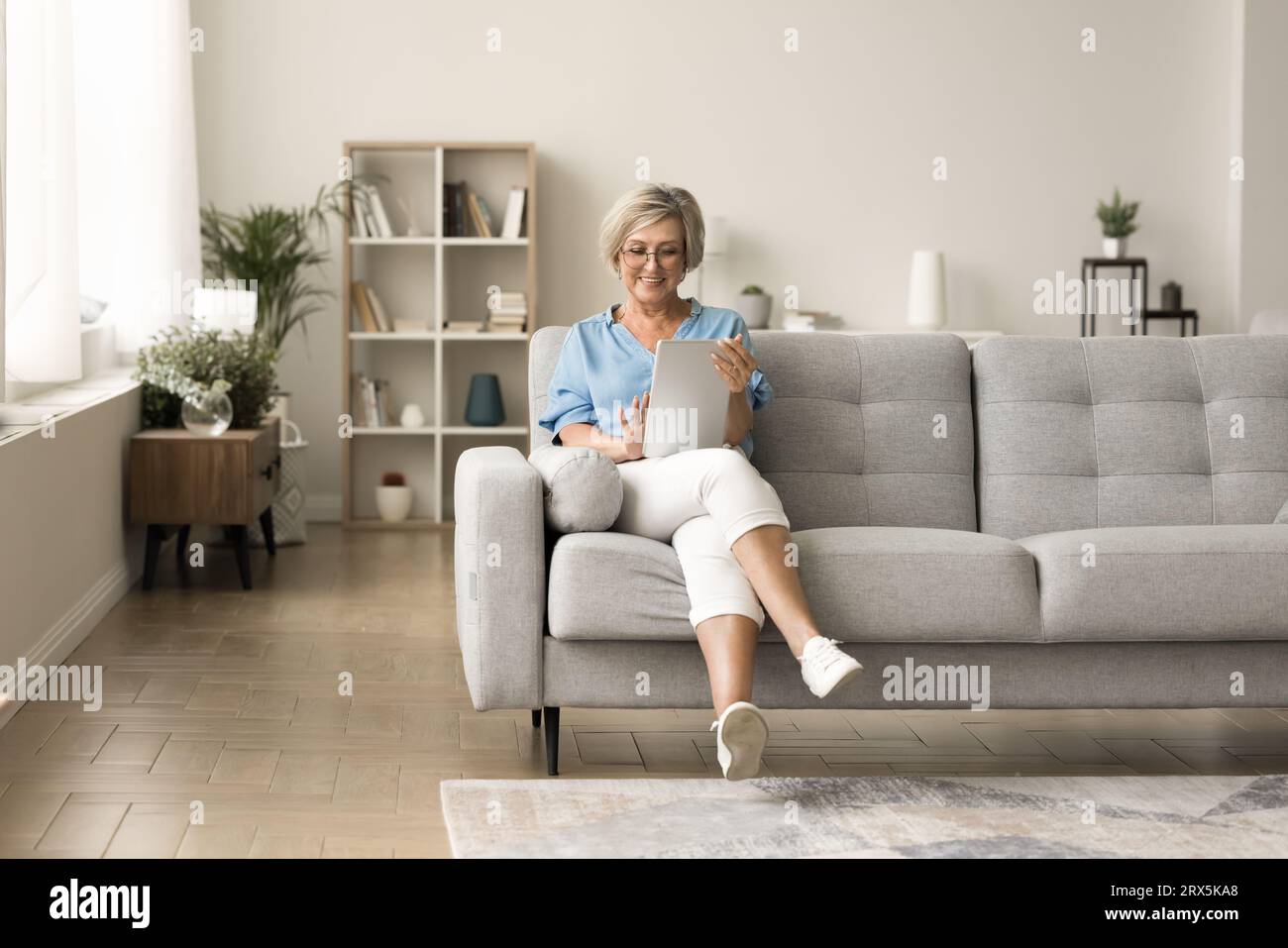 Happy pretty elderly mature woman using tablet computer Stock Photo