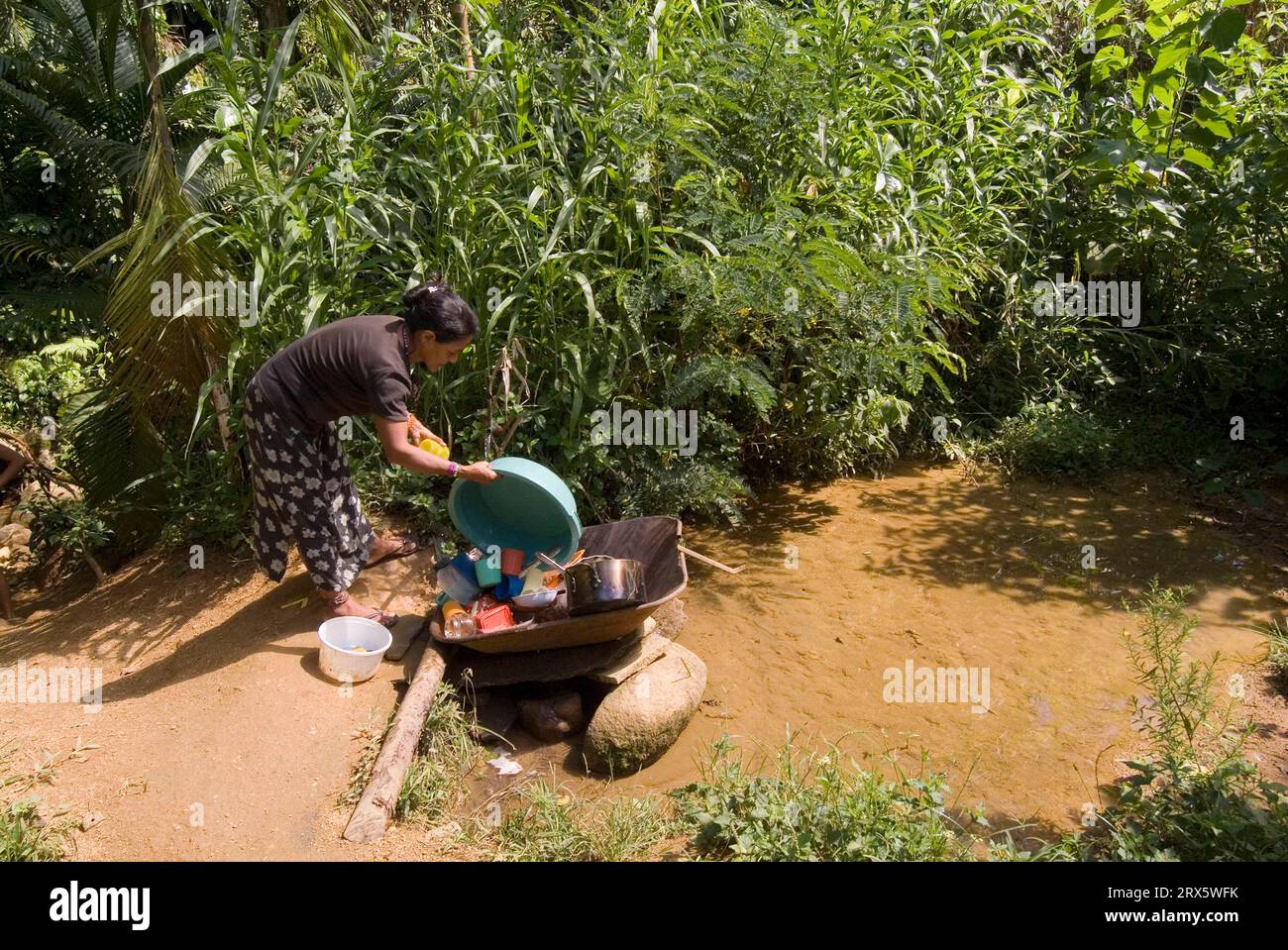 Guarani Indian woman washing dishes in the stream, Boa Vista village, Sao Paulo state, Brazil Stock Photo