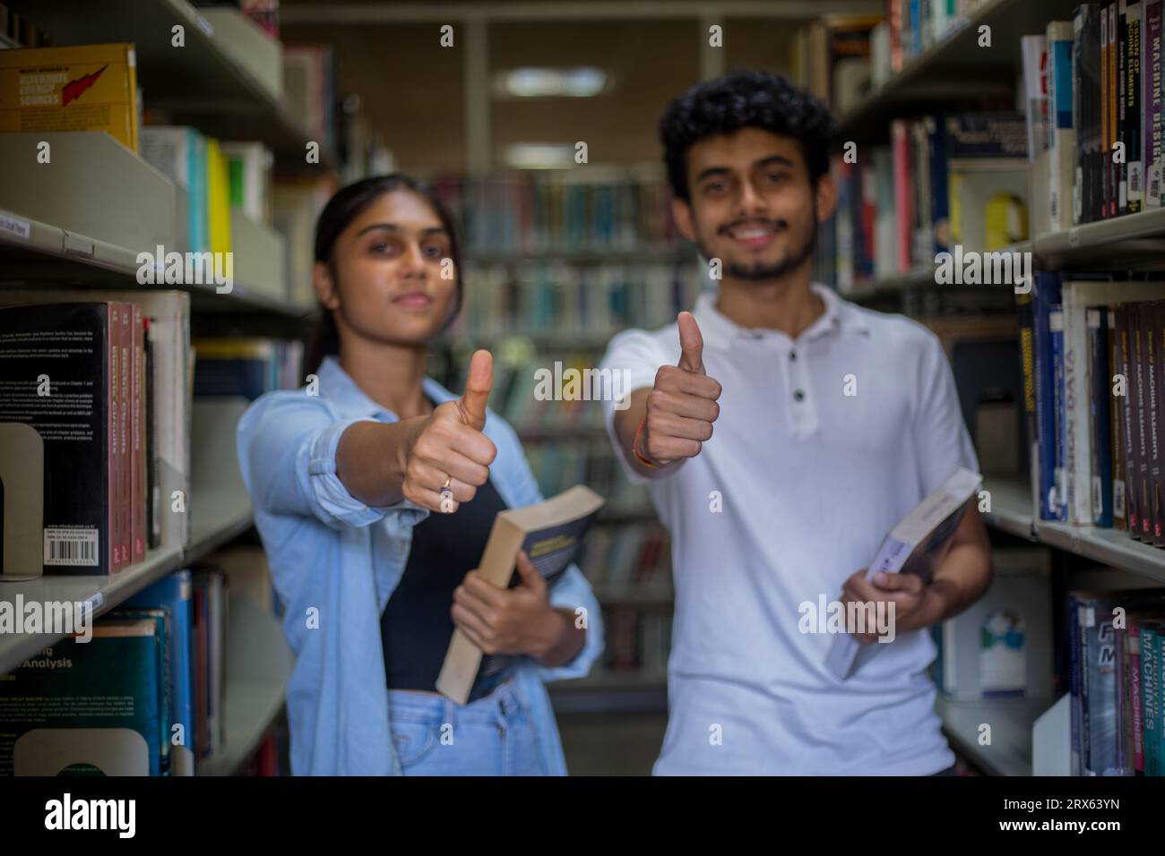 Attractive students standing in the library showing thumbs up Stock ...