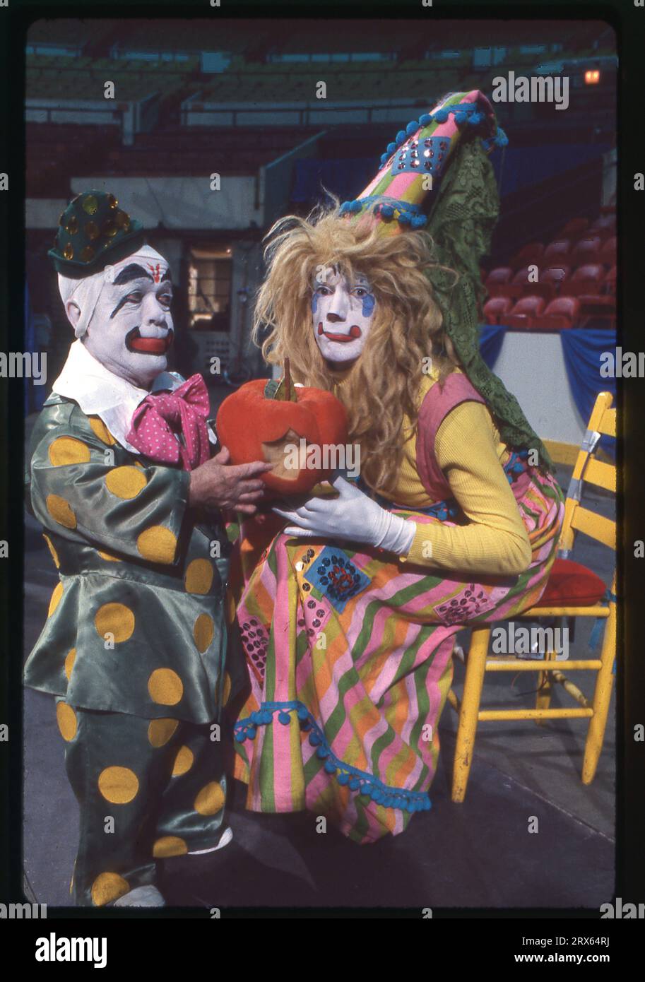 Photo of 2 Ringling Brothers clowns in full makeup holding a pumpkin that seems to have been bitten. At Clown College auditions in 1979. The clown to the left is Prince Paul. Stock Photo