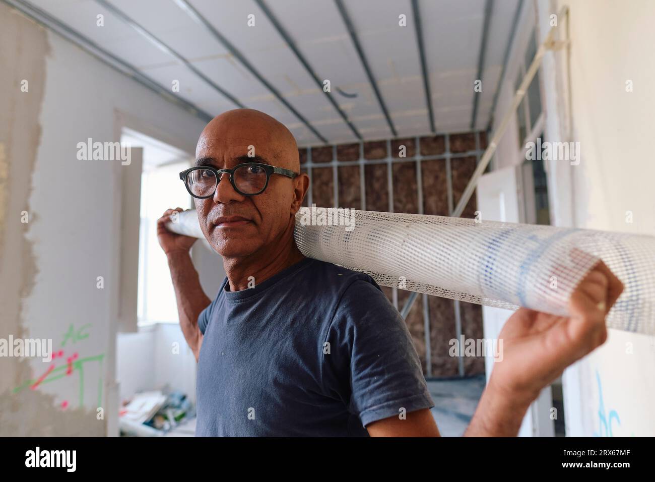 Mature construction worker standing with mesh roll at site Stock Photo