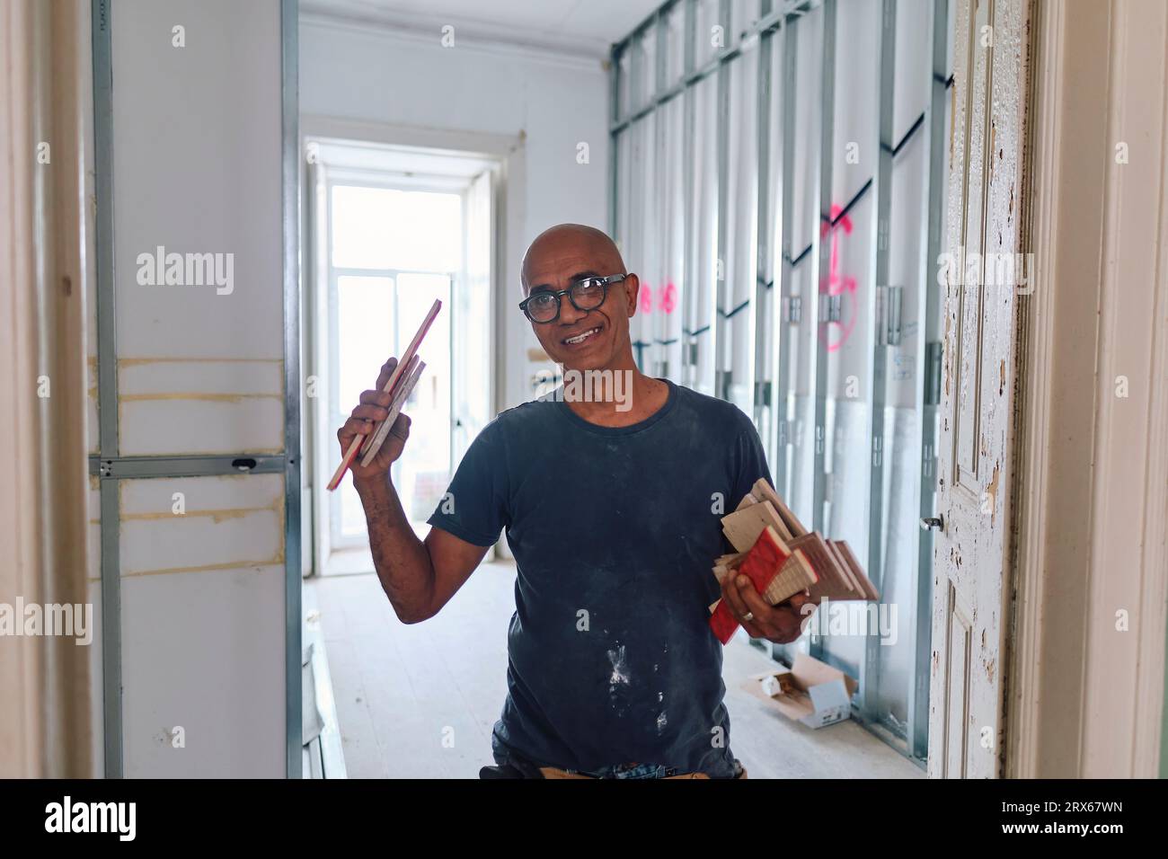 Happy construction worker holding tile samples at site Stock Photo