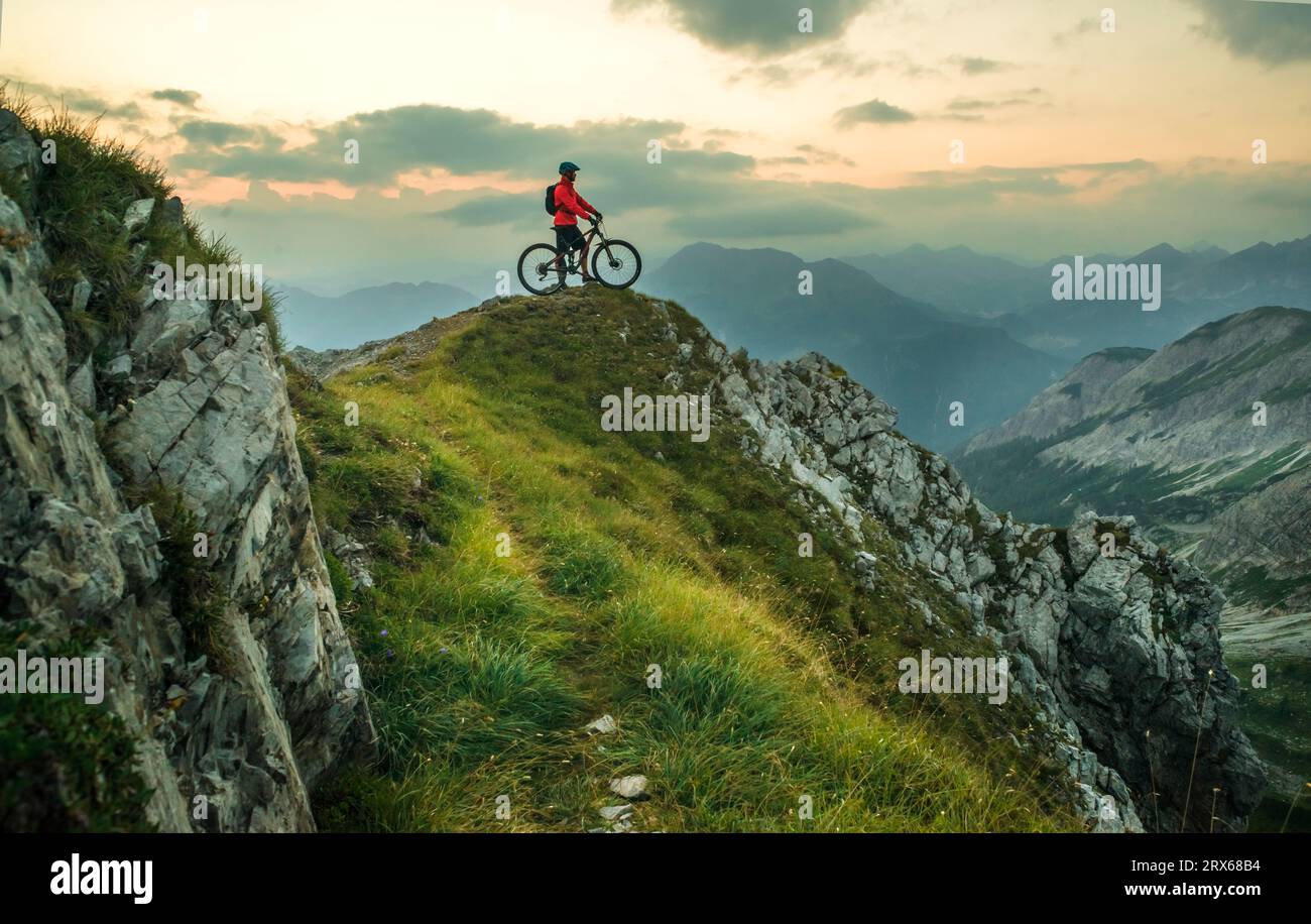 Active man with bicycle on mountain at sunset Stock Photo
