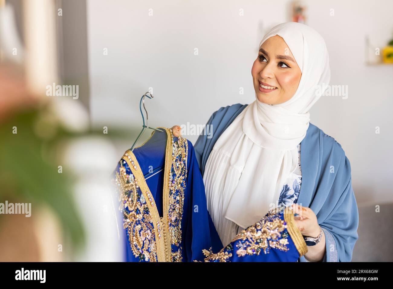 Happy young fashion designer with blue wedding dress Stock Photo - Alamy