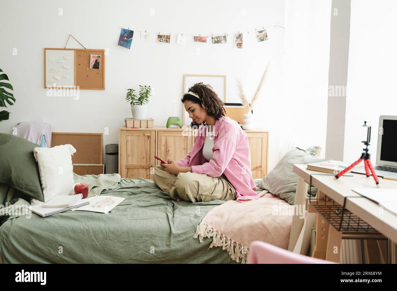 Smiling teenage girl using mobile phone on bed at home Stock Photo - Alamy