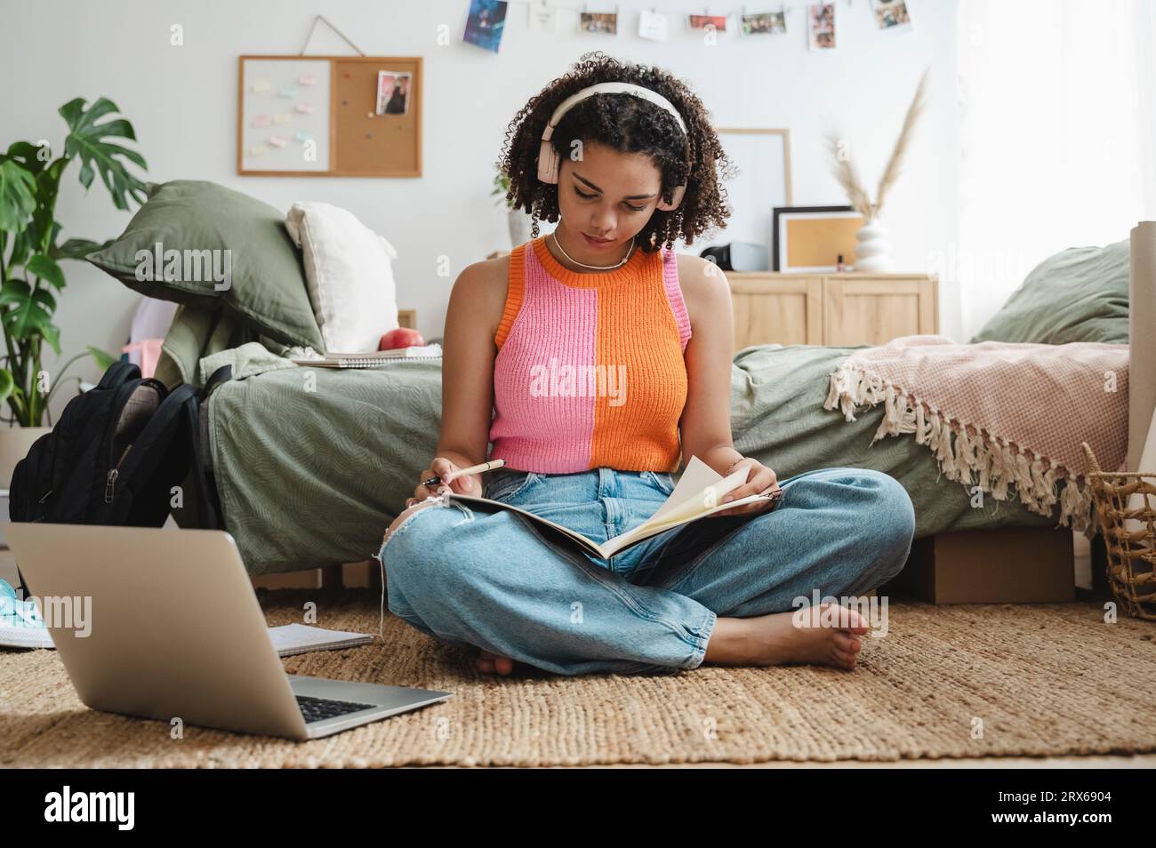 Teenage girl wearing wireless headphones doing homework at home Stock