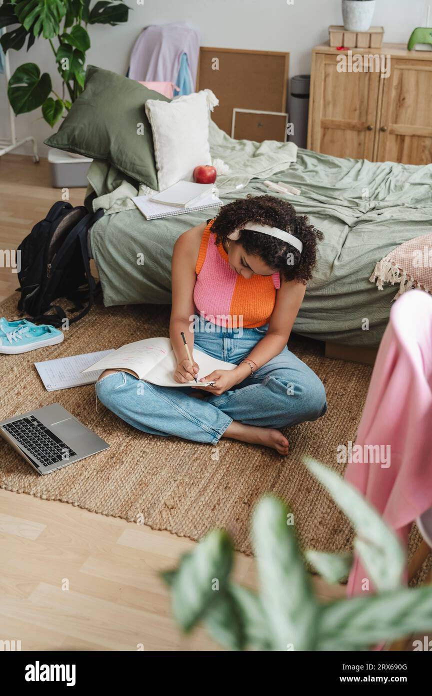 Teenage girl writing in book sitting on rug at home Stock Photo - Alamy