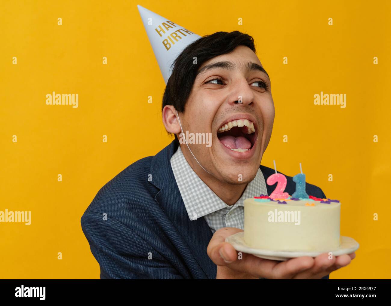 Cheerful man holding 21st birthday cake in studio Stock Photo