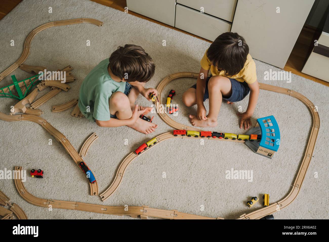 Boys playing with toy train on carpet at home Stock Photo Alamy