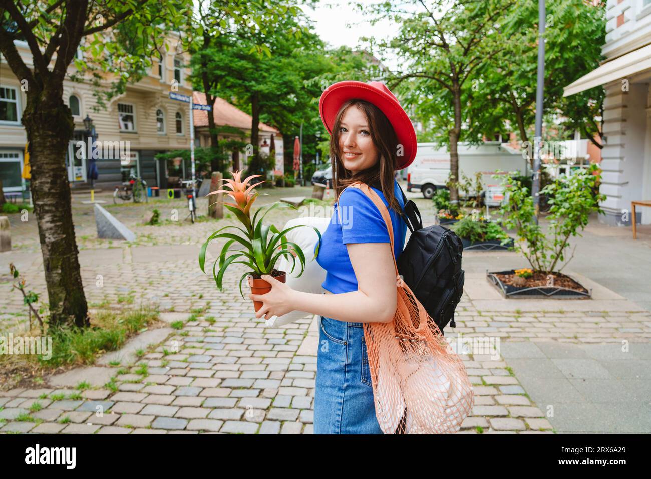 Teenage girl carrying potted plant and pillow on footpath Stock Photo ...