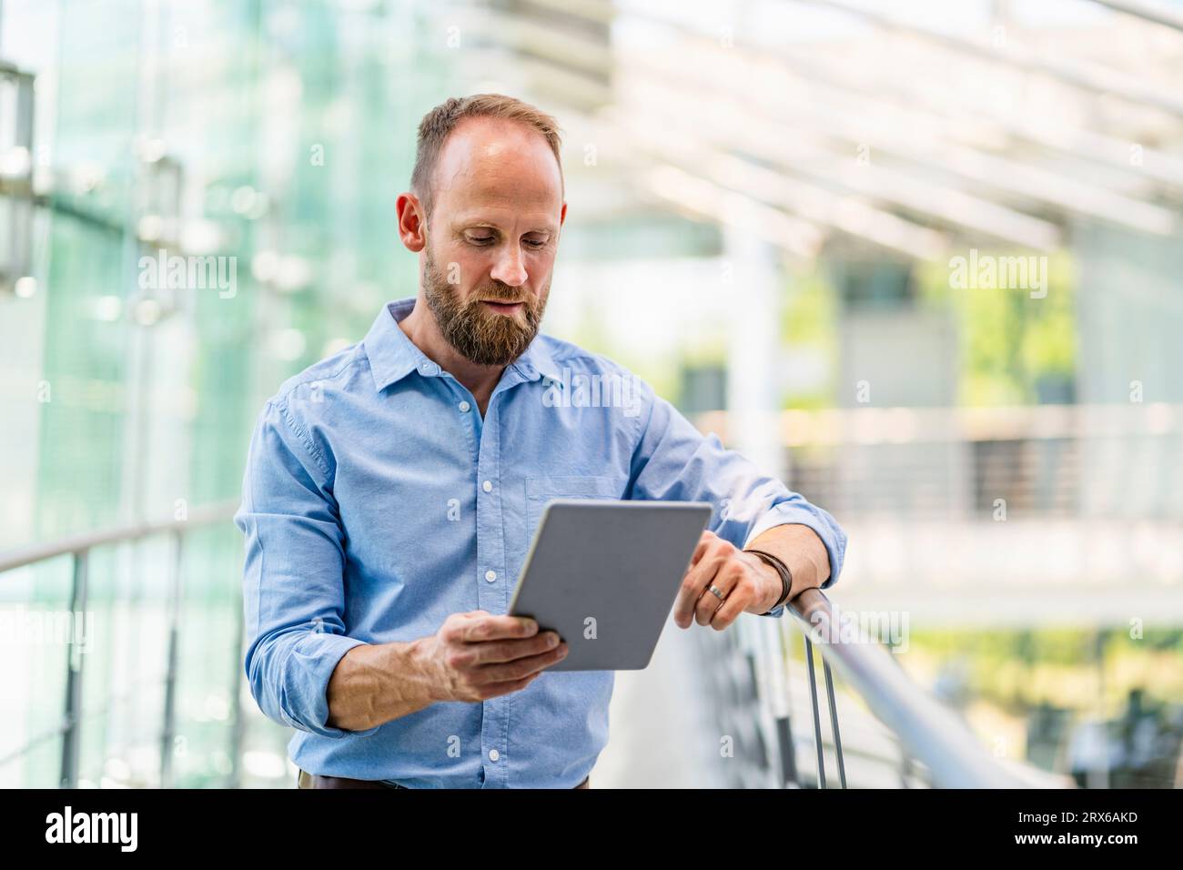 Experienced businessman using digital tablet standing in office building Stock Photo