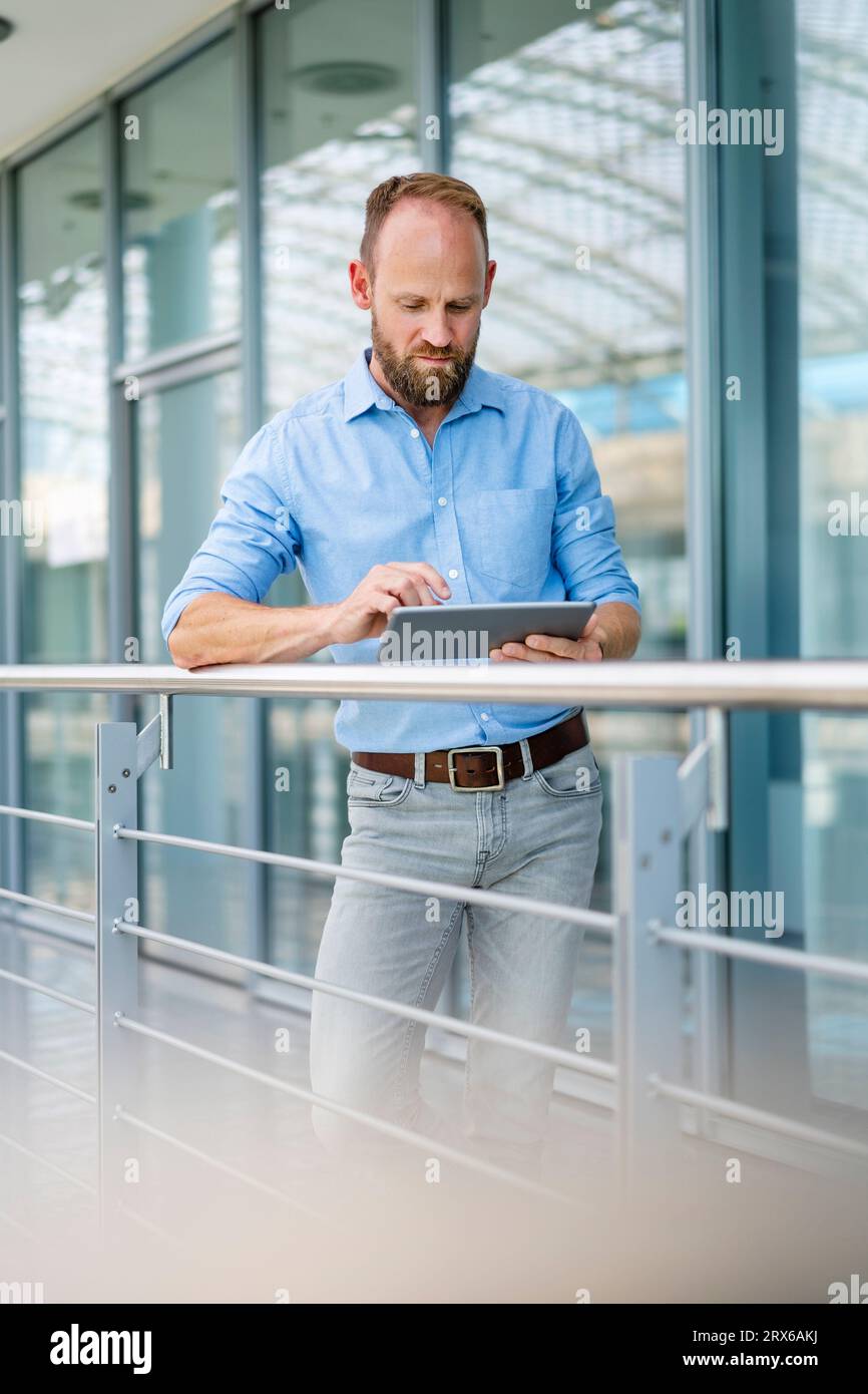 Experienced businessman using digital tablet standing in office building Stock Photo