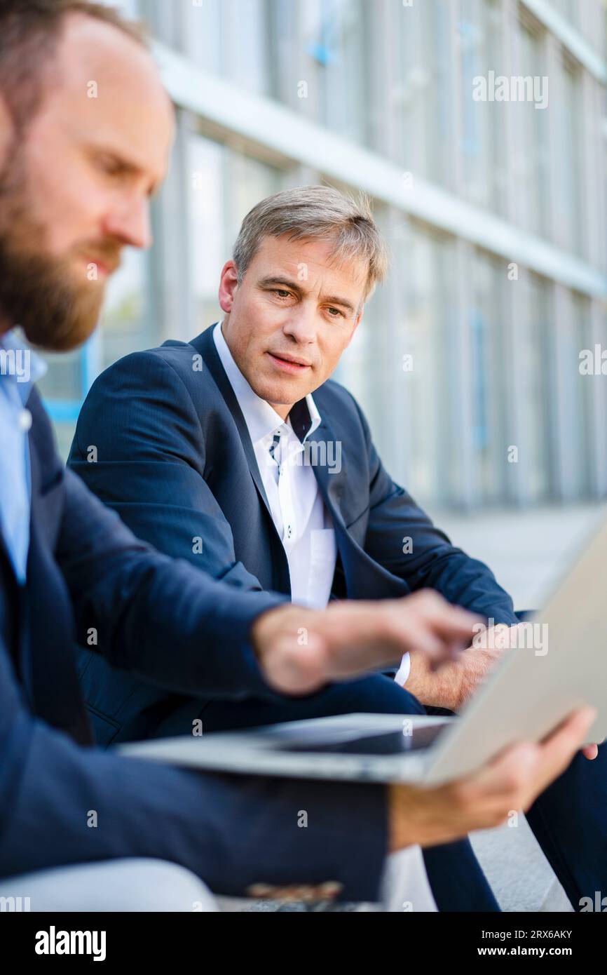 Two business colleagues sitting on steps working together on laptop Stock Photo