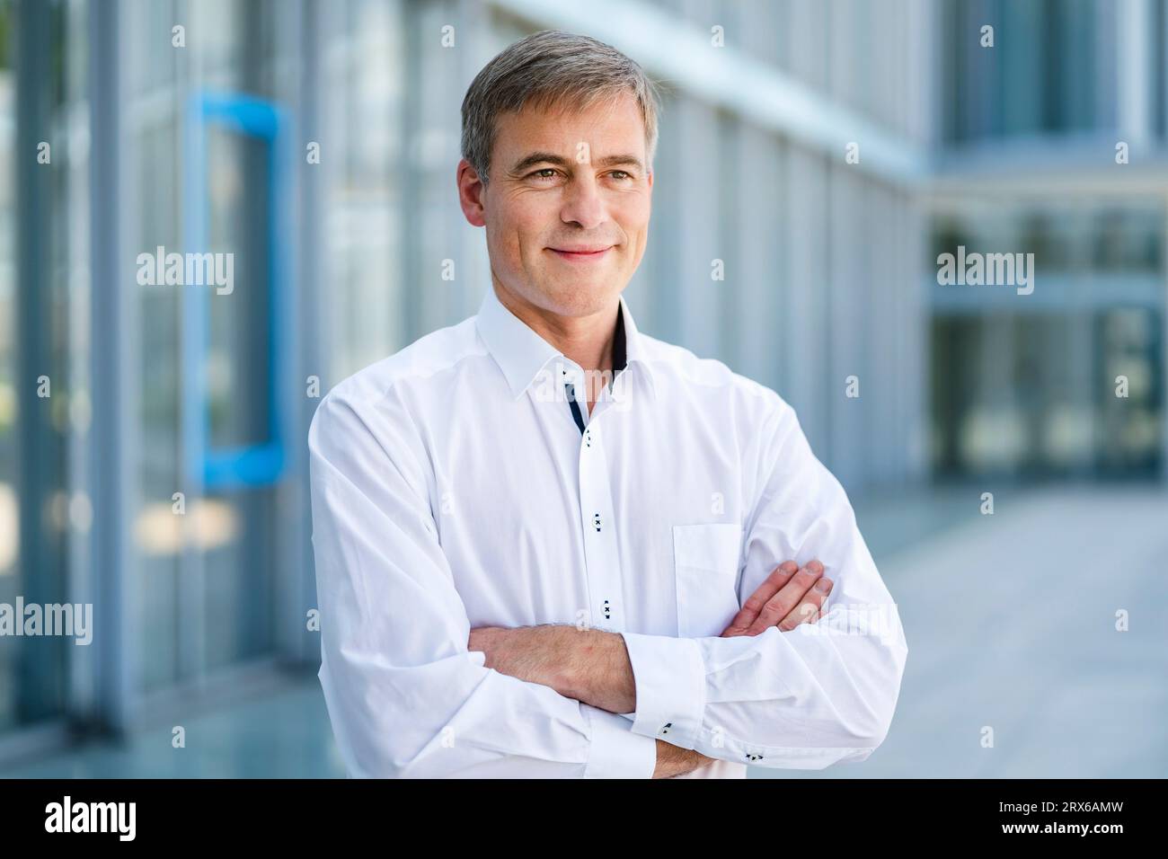 Casual businessman standing in front of office building with arms crossed Stock Photo