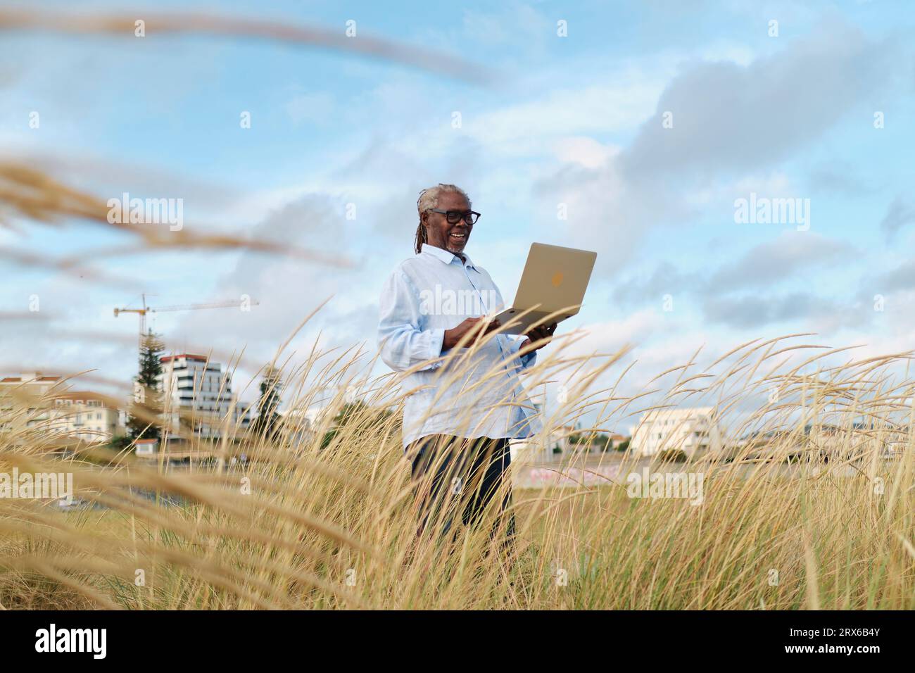 Smiling engineer using laptop in field Stock Photo