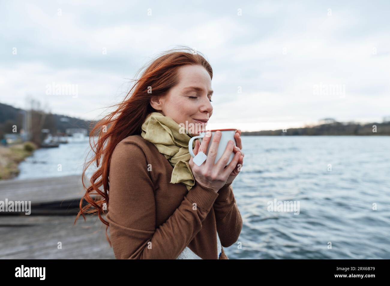 Woman having tea by lake Stock Photo