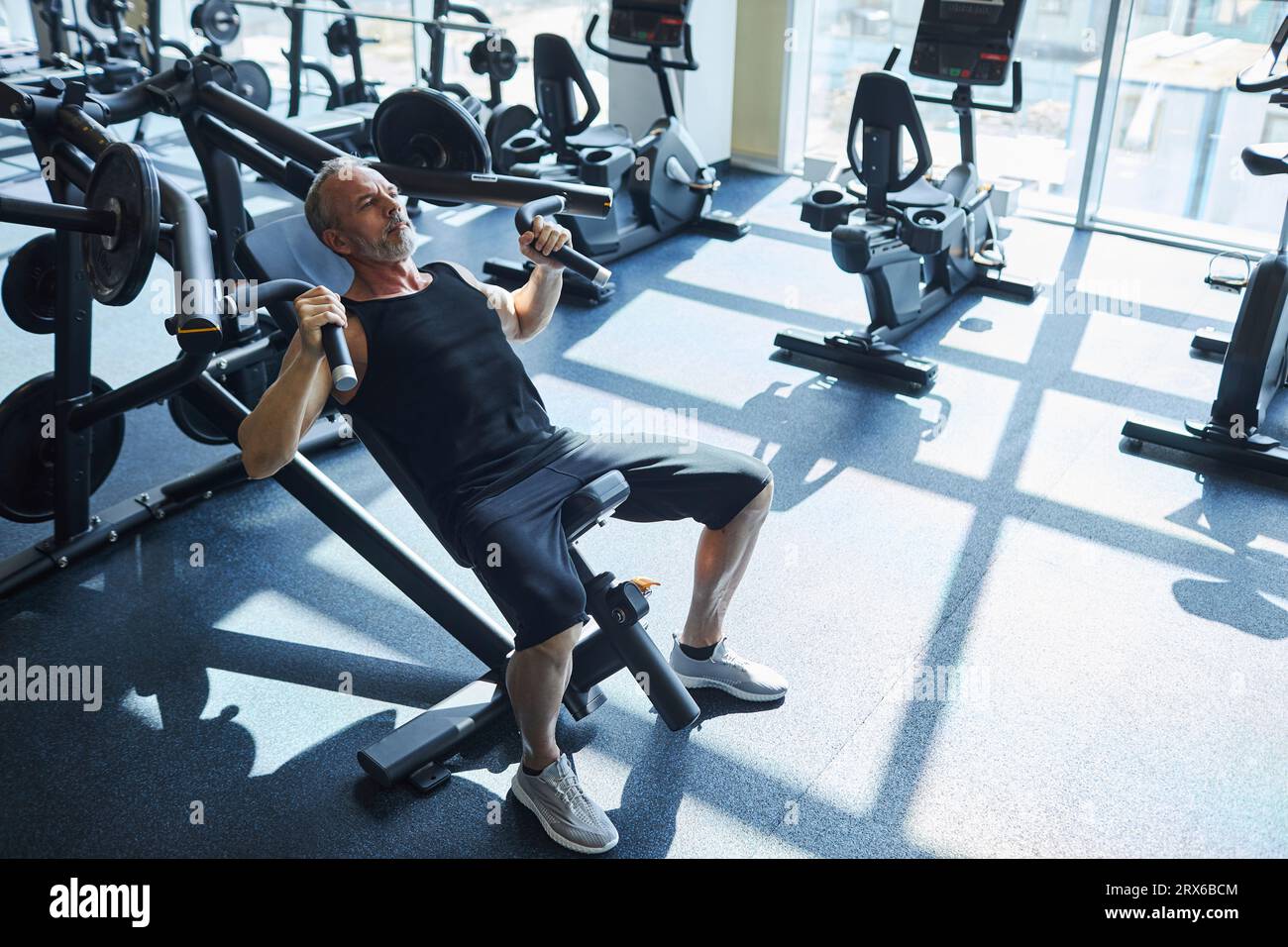 Mature man doing strength training exercise in gym Stock Photo