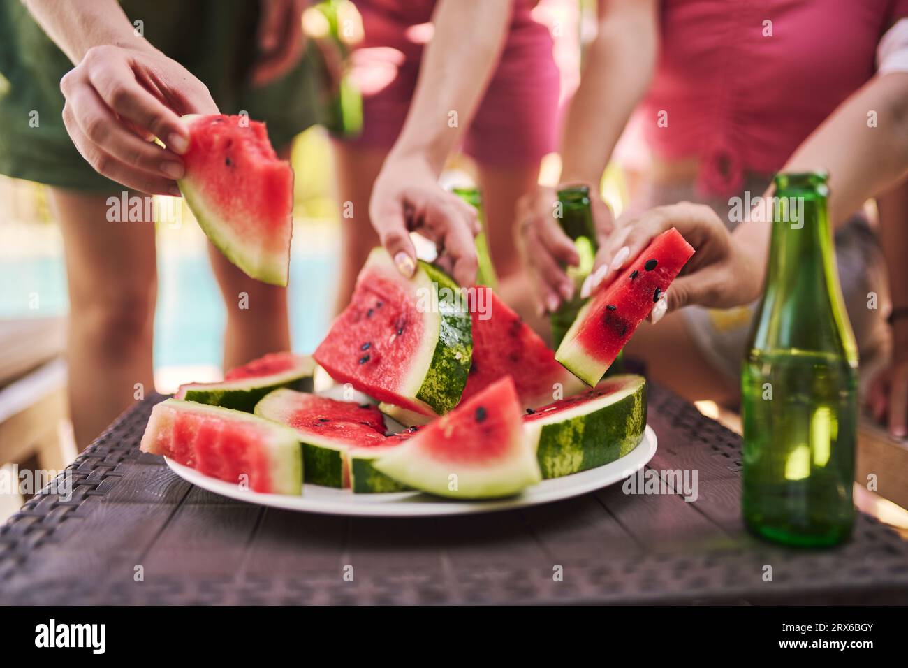 Hands of friends holding slices of watermelon at table Stock Photo