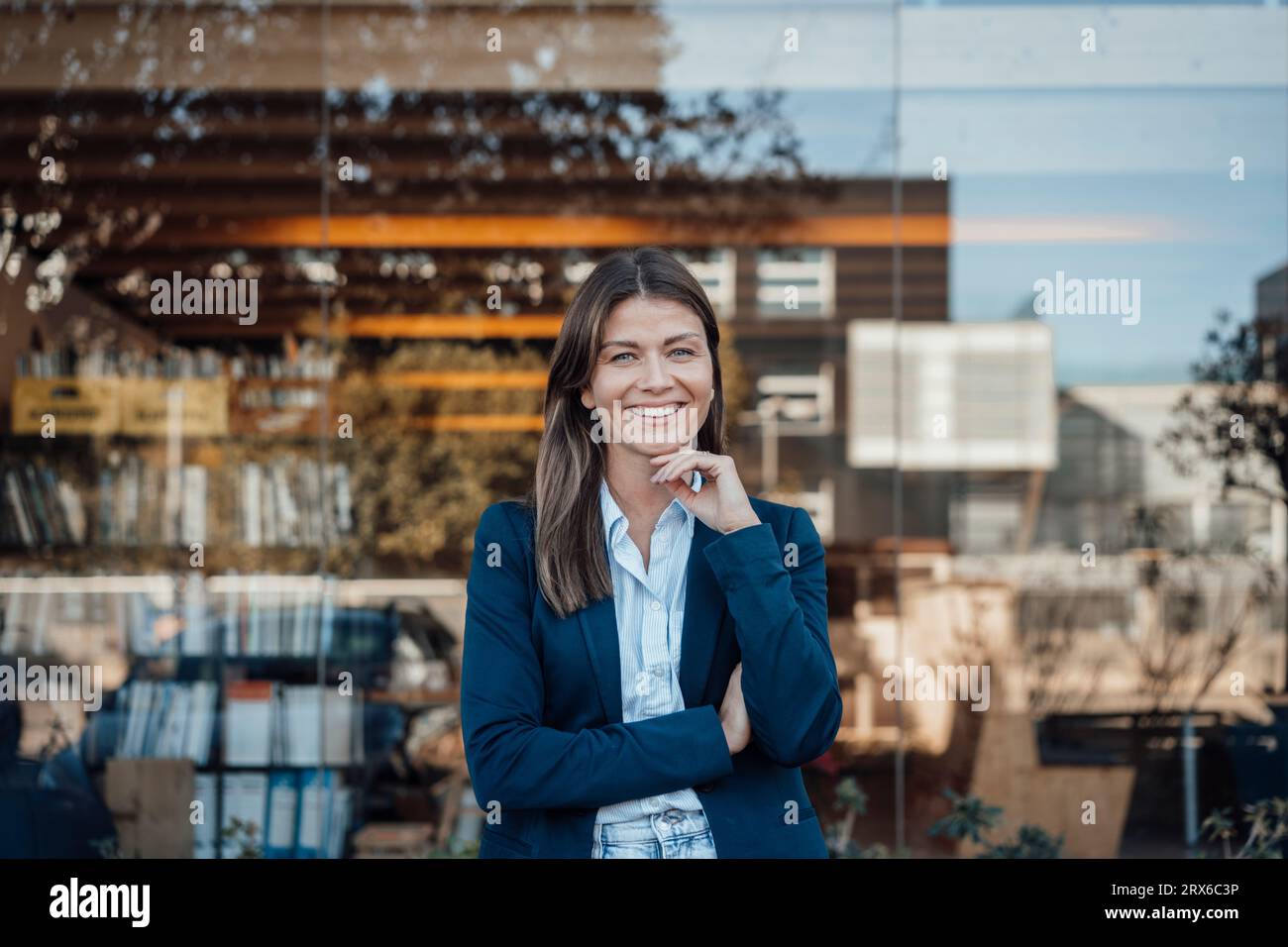 Smiling businesswoman wearing blazer standing in front of glass Stock Photo