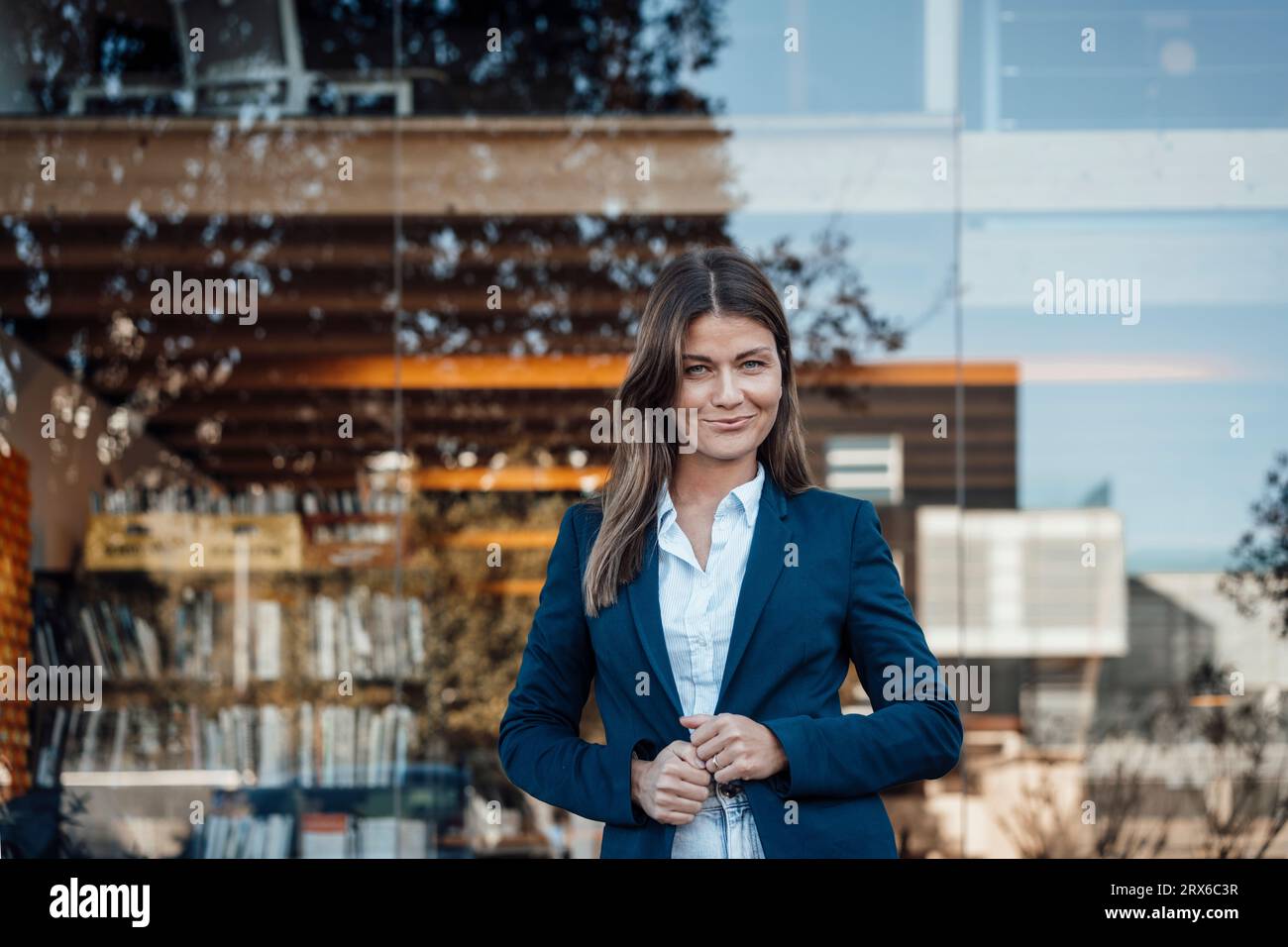Happy businesswoman wearing blazer standing in front of glass Stock Photo