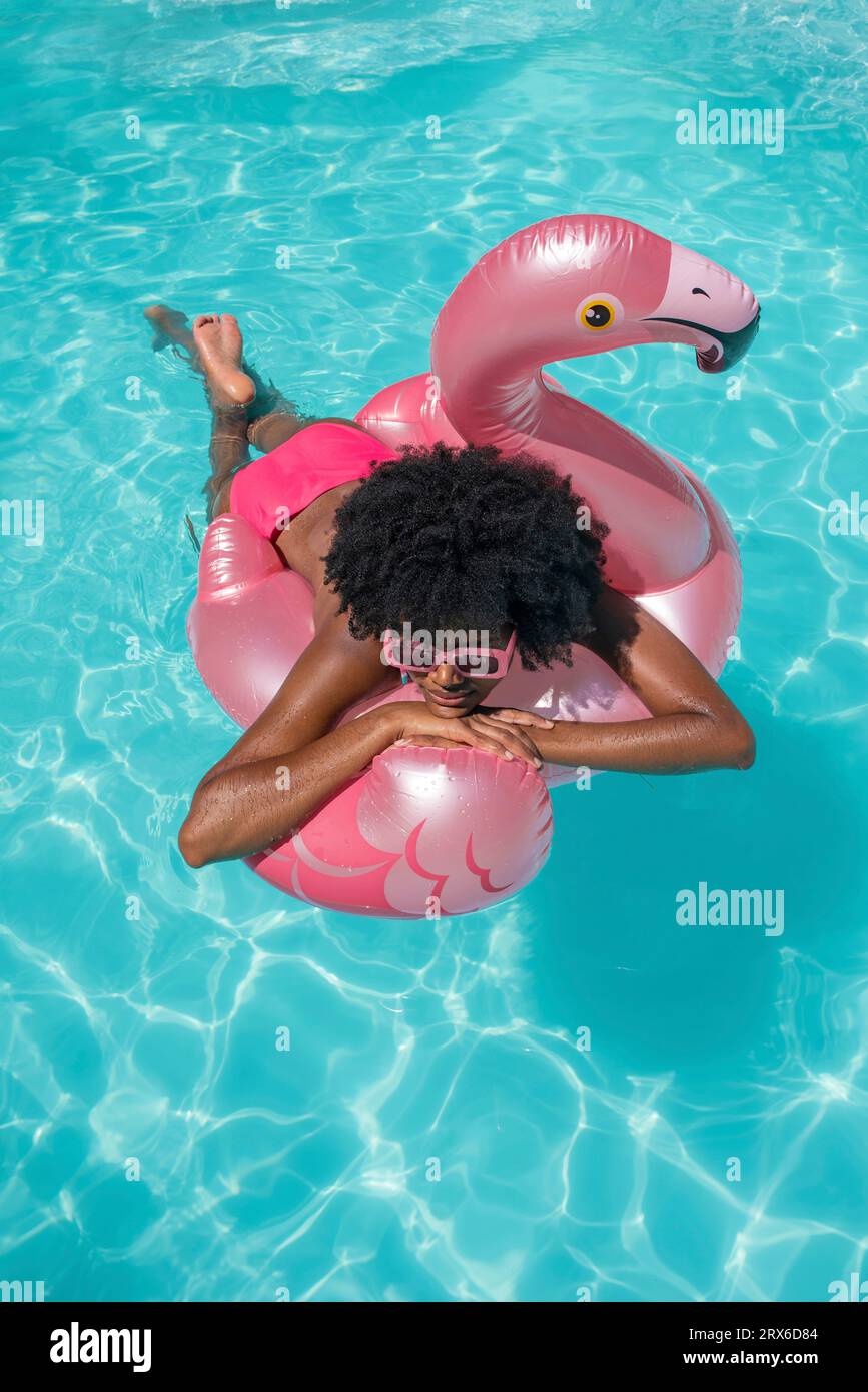 Woman relaxing on swimming float in pool Stock Photo