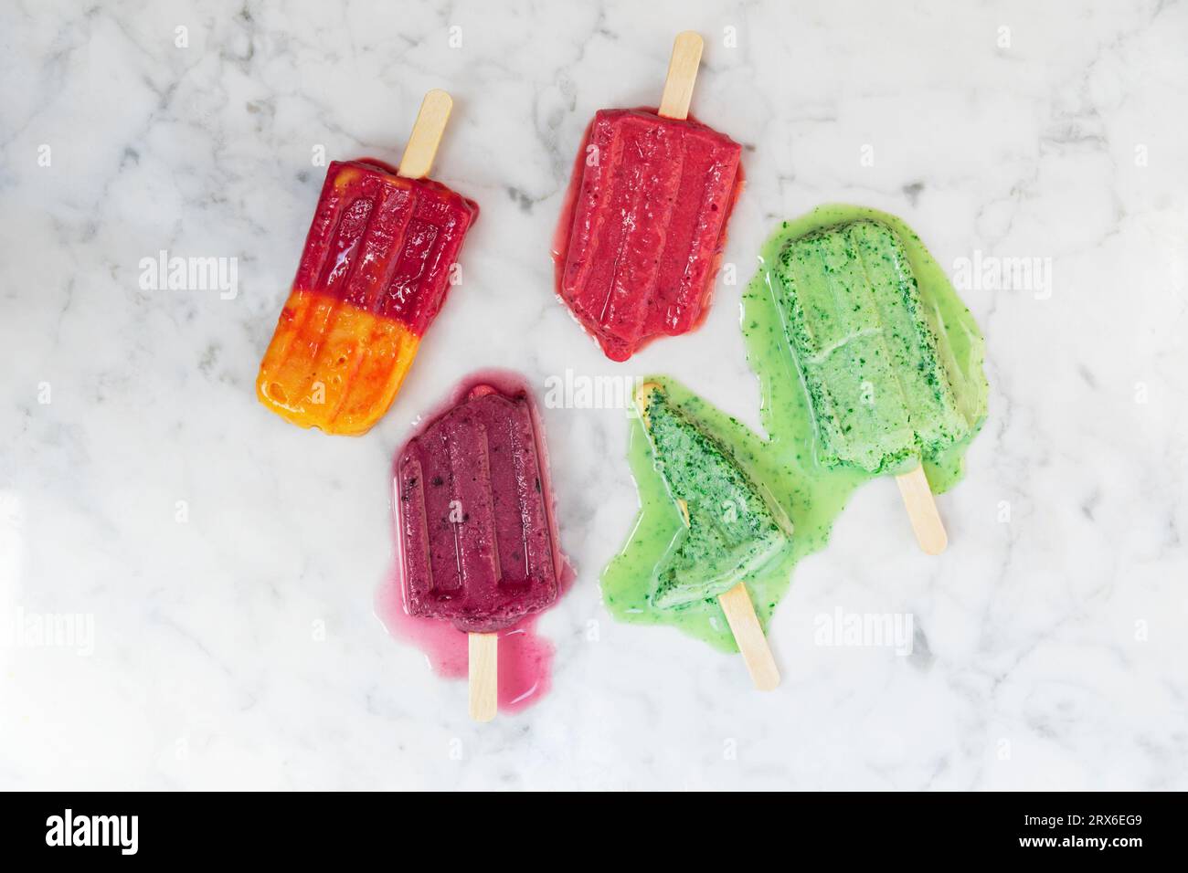 Homemade berry fruit popsicles melting against marble surface Stock Photo