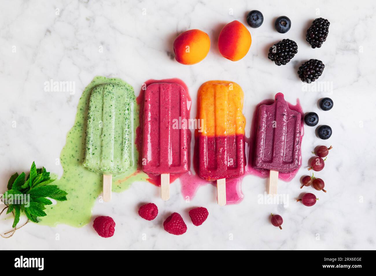 Berry fruits and melting popsicles on marble surface Stock Photo