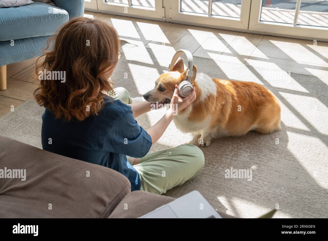 Young woman wearing wireless headphones to pet dog Stock Photo