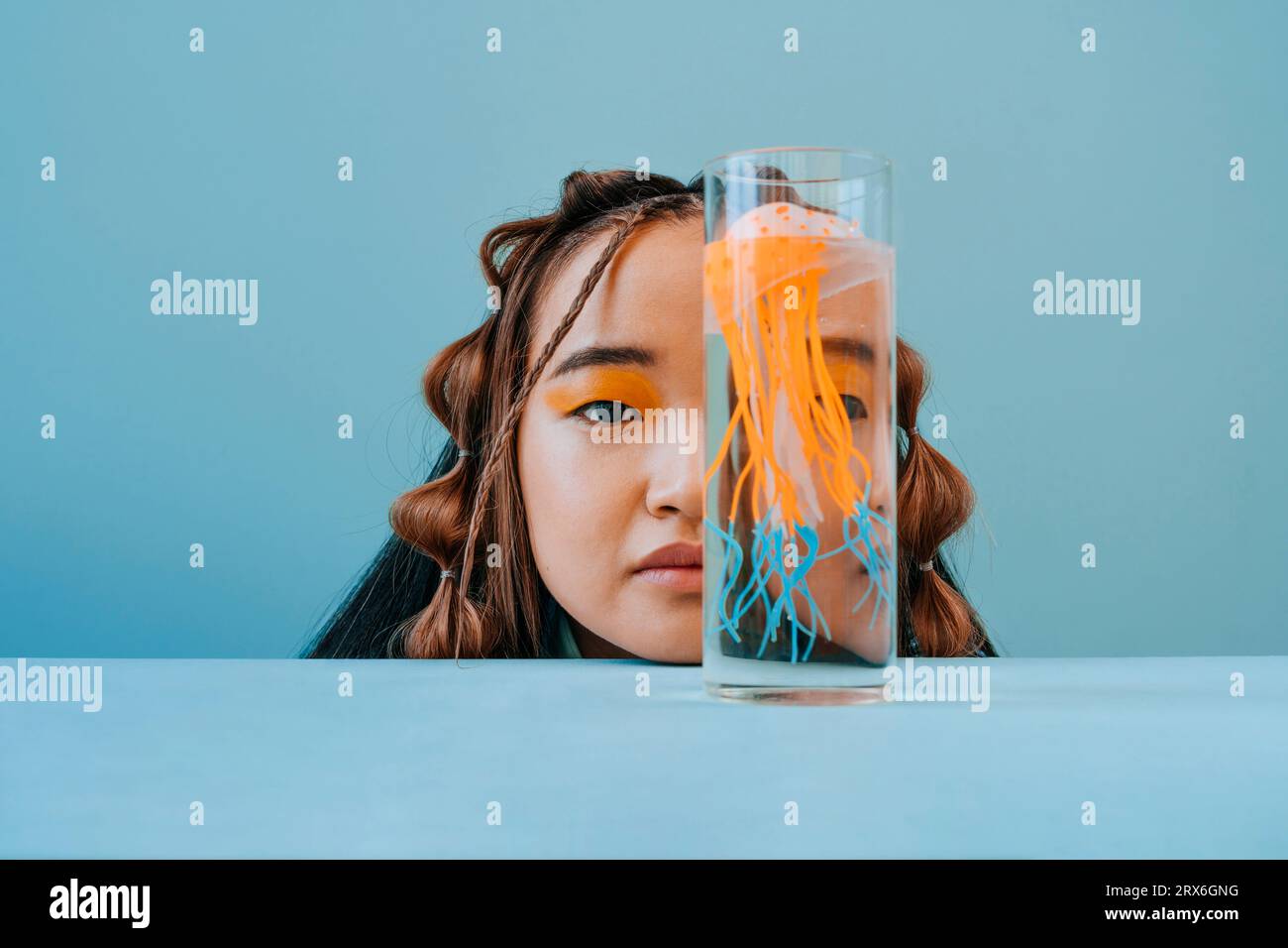 Young woman covering half face with jellyfish in glass Stock Photo Alamy