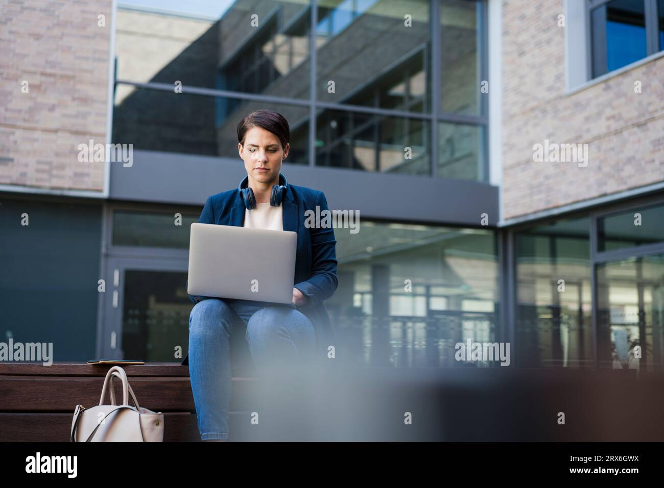 Businesswoman using laptop and sitting on bench Stock Photo