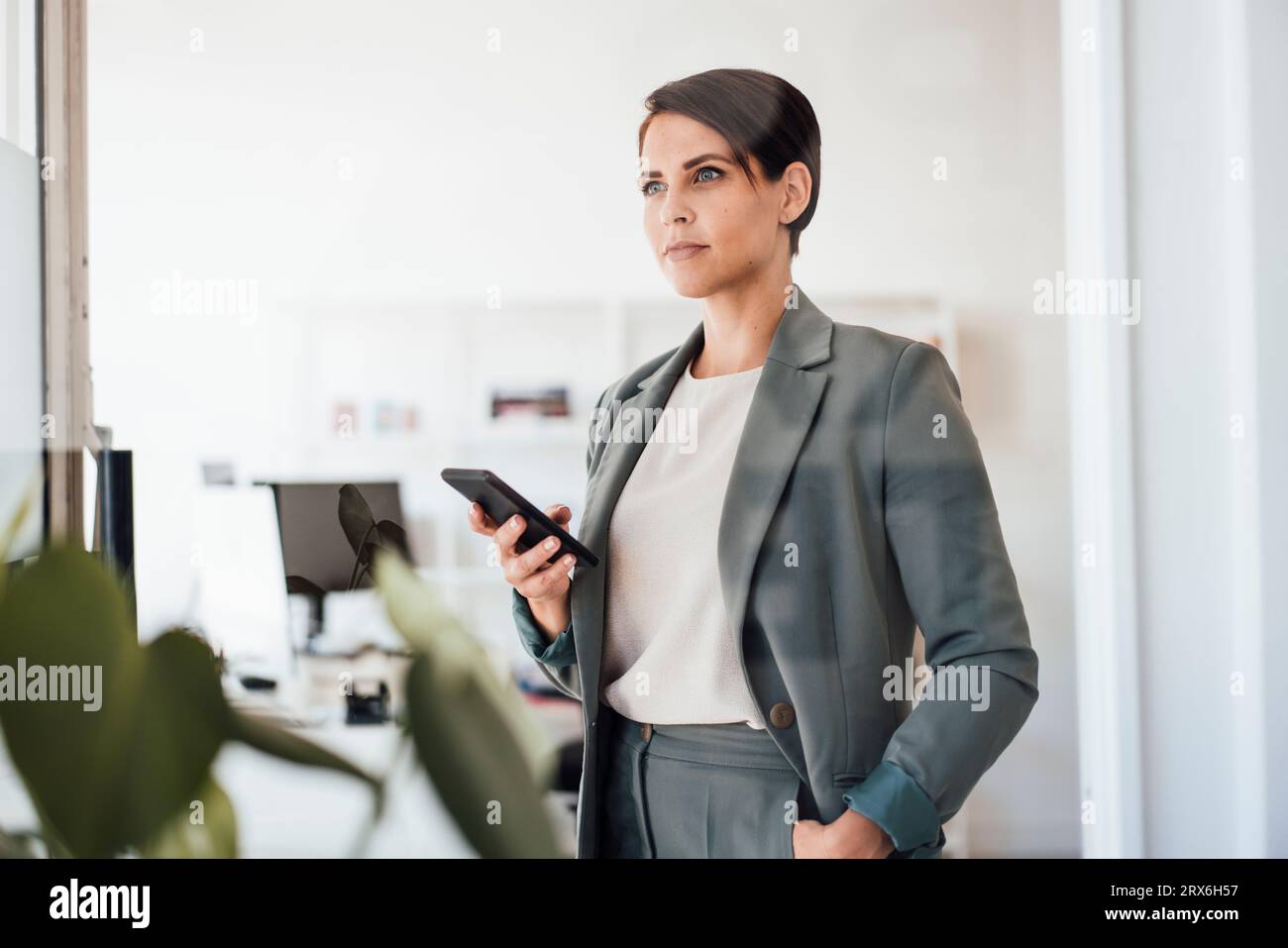 Confident businesswoman with smart phone in office Stock Photo
