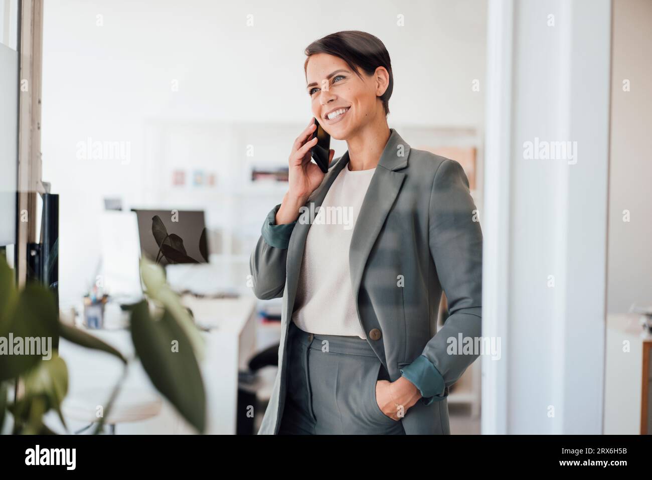 Happy businesswoman talking on smart phone at workplace Stock Photo