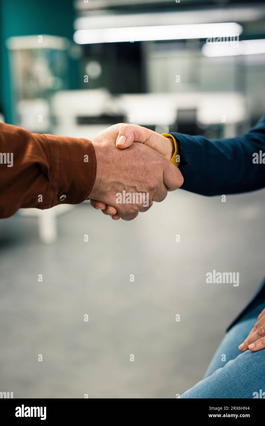 Business colleagues shaking hands at work place Stock Photo