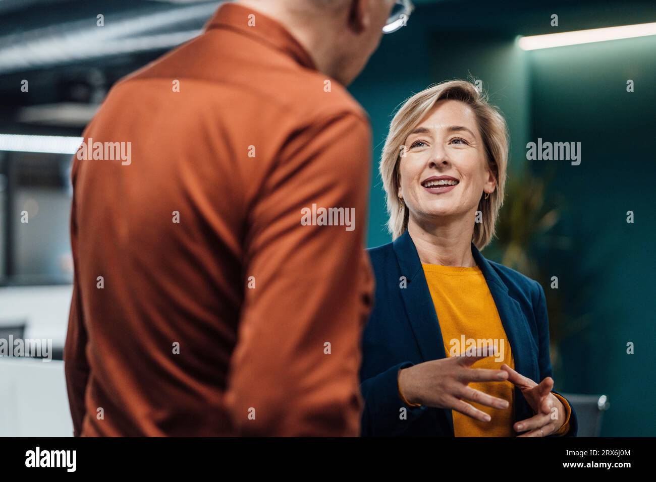 Smiling blond businesswoman discussing with colleague in office Stock Photo