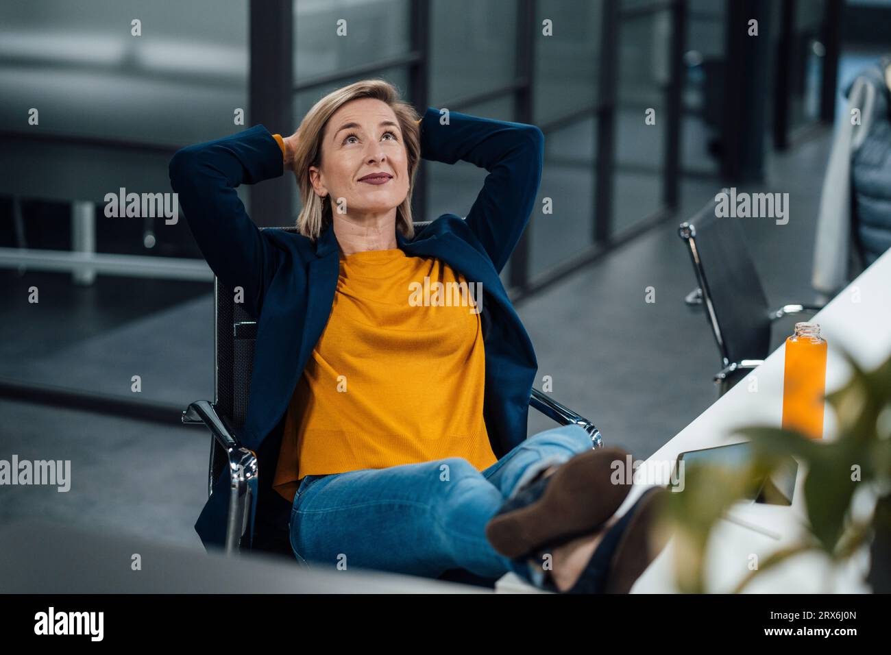 Thoughtful businesswoman with hands behind head relaxing in office Stock Photo