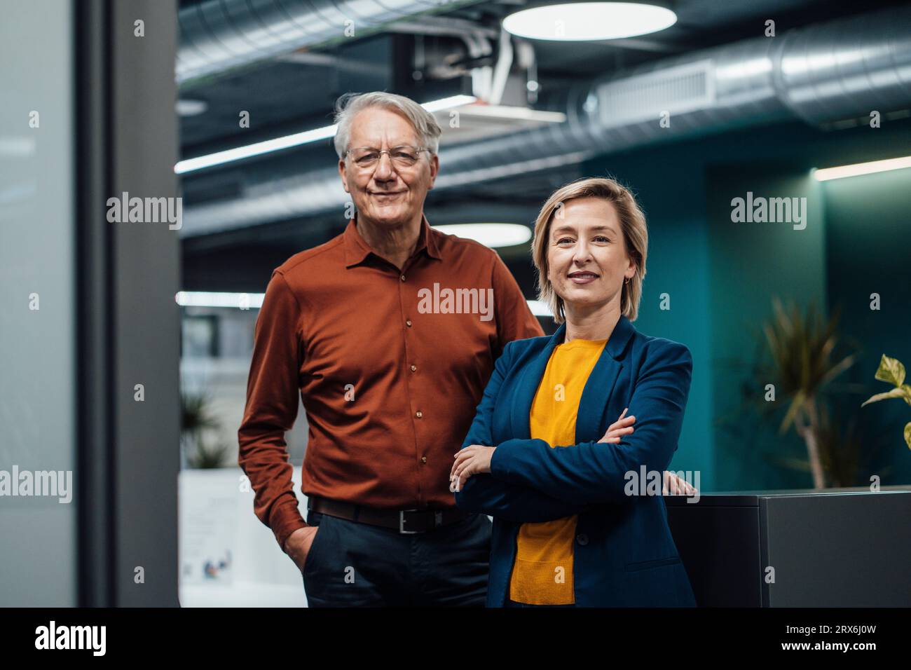Smiling businesswoman and businessman in illuminated office Stock Photo