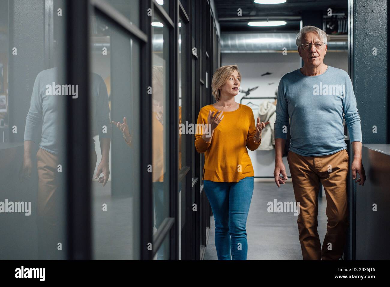 Businesswoman discussing with colleague and walking in office Stock Photo