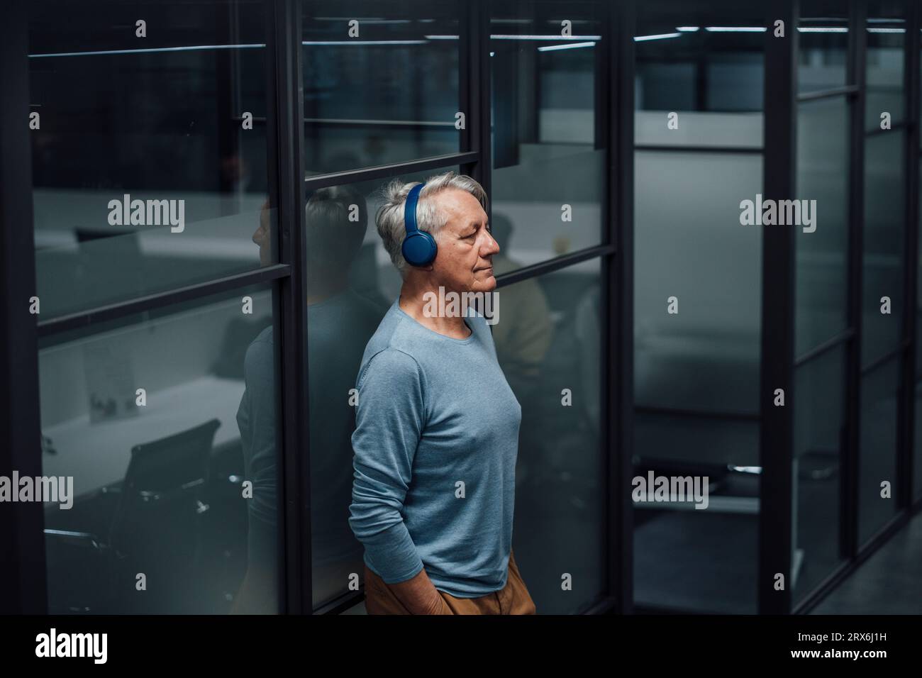 Senior businessman listening music on headphones at work place Stock Photo