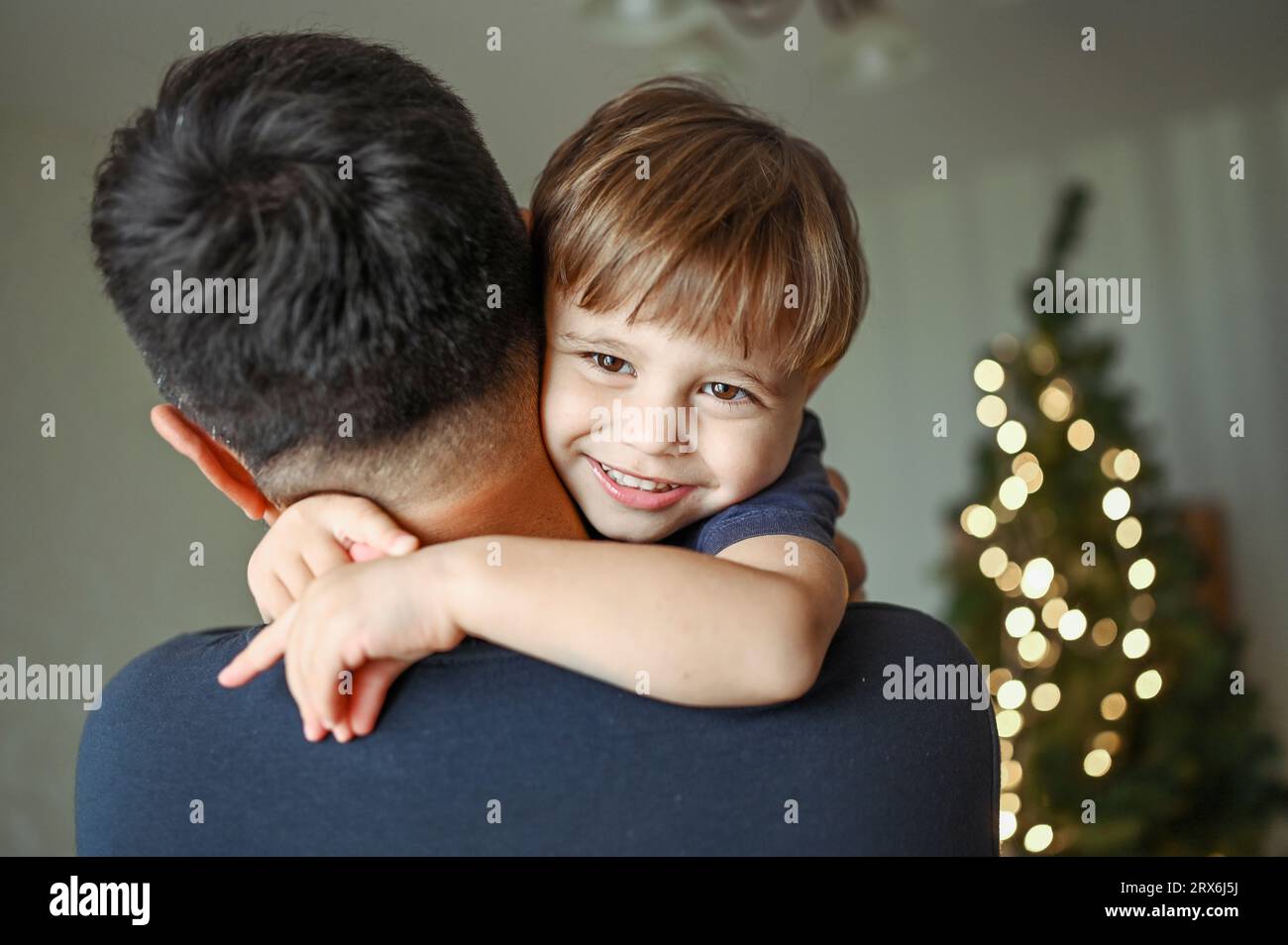 Father embracing smiling son at home Stock Photo