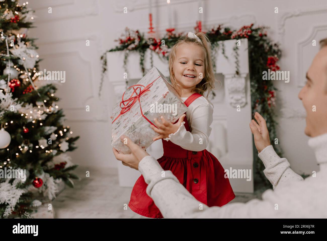 Happy daughter holding present near christmas tree Stock Photo
