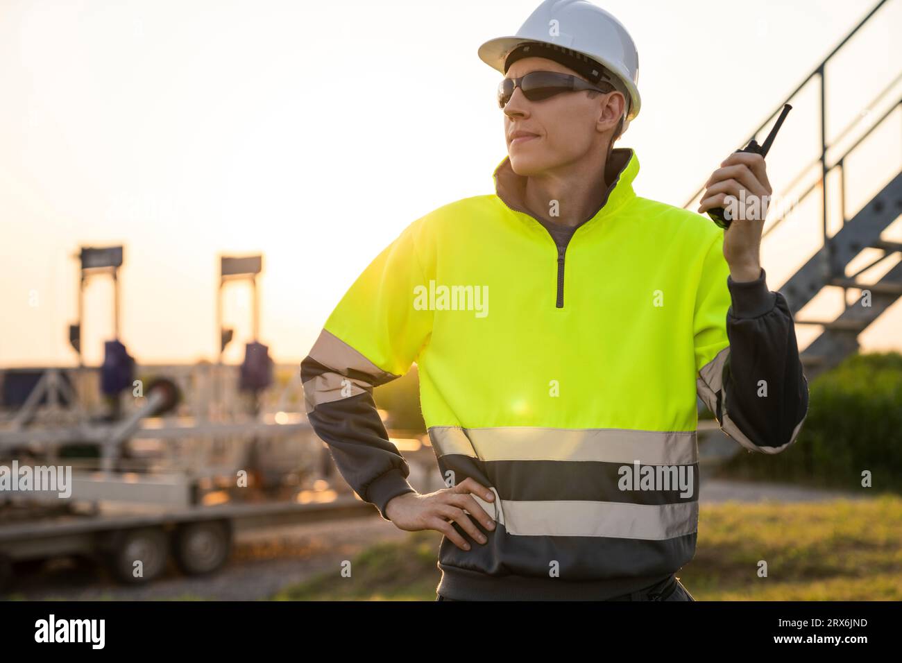 Engineer holding walkie-talkie and standing in field Stock Photo