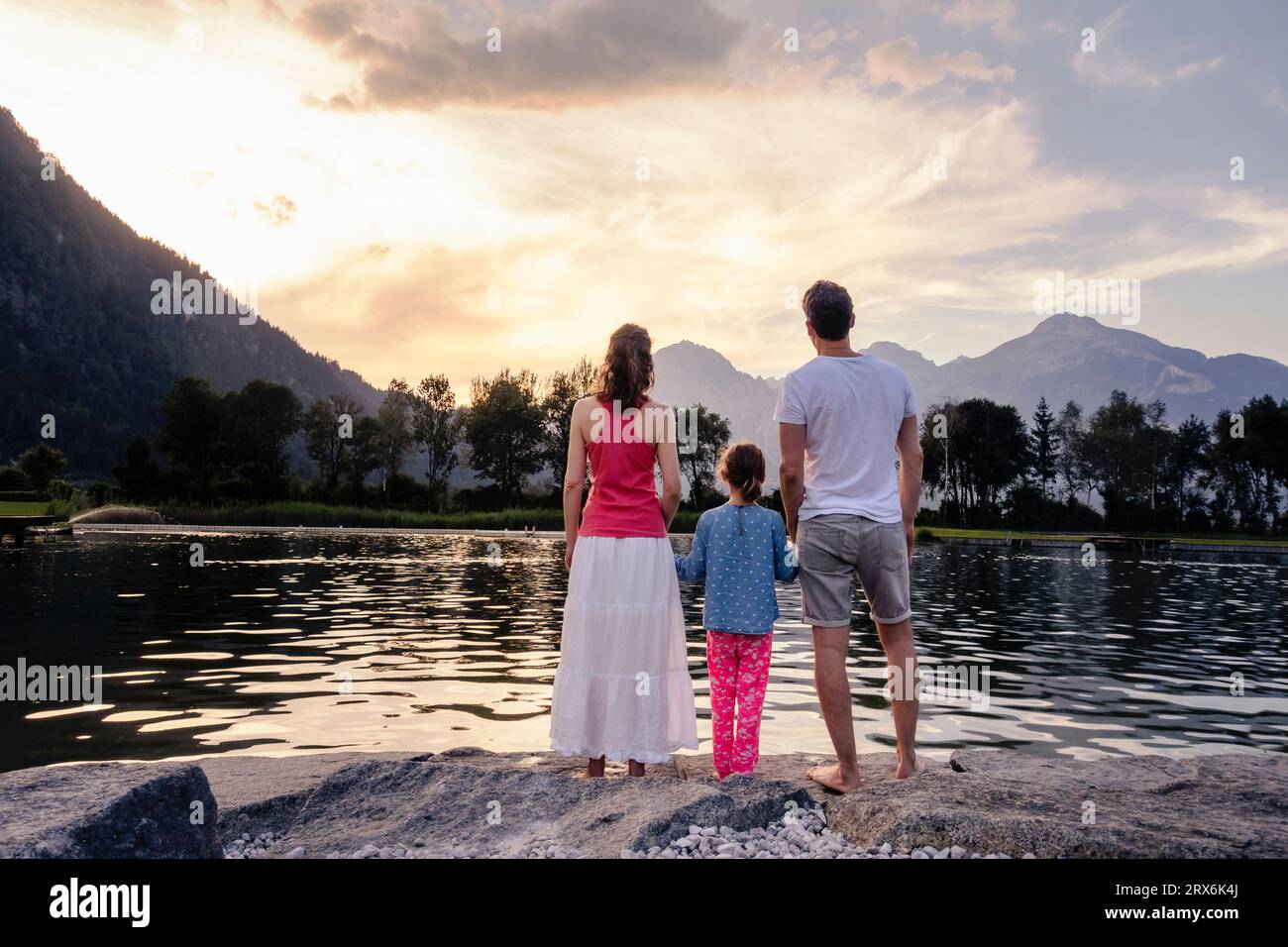 Family admiring lake and mountains at sunset Stock Photo