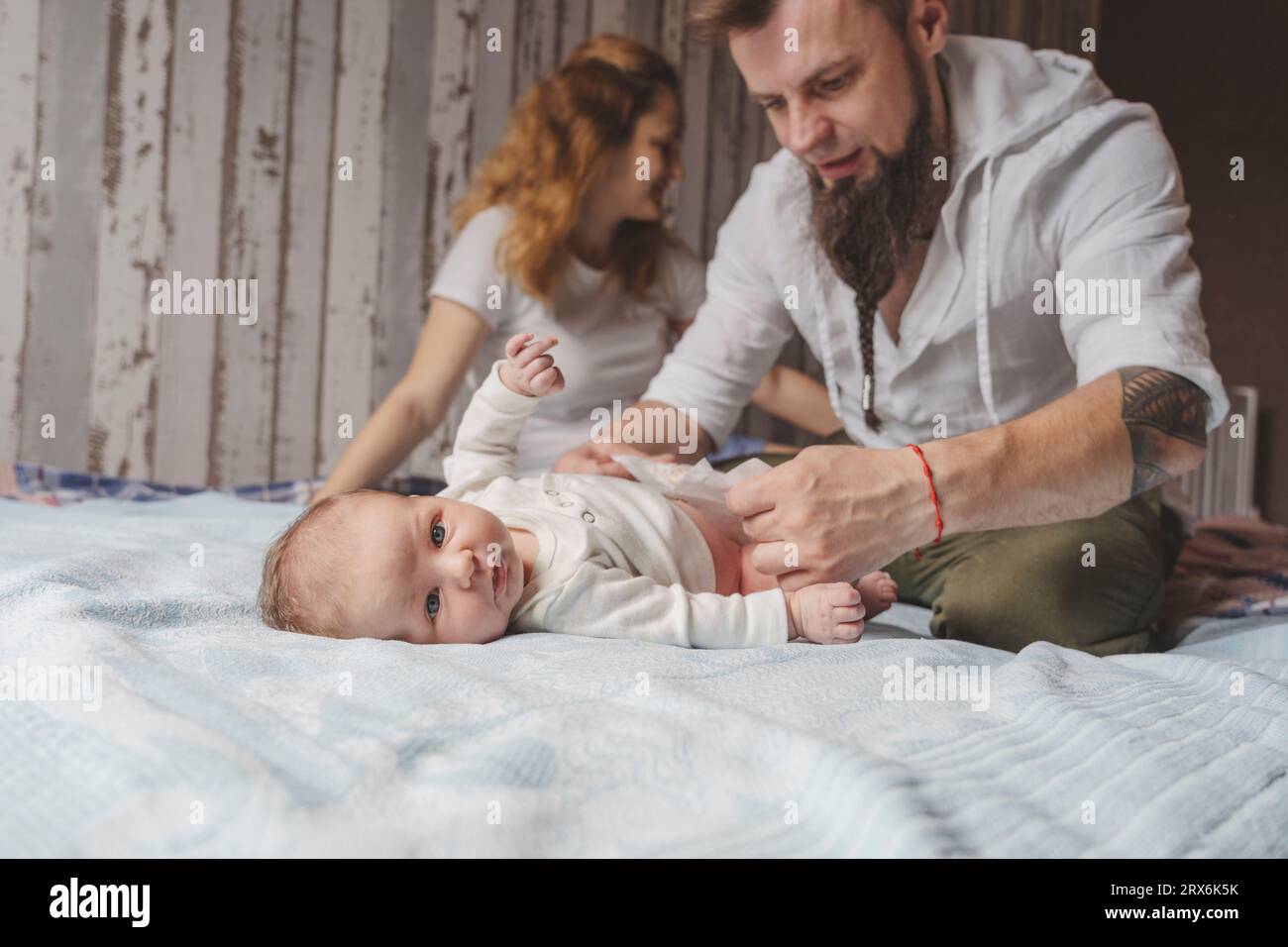 Father changing newborn daughter's diaper on bed at home Stock Photo