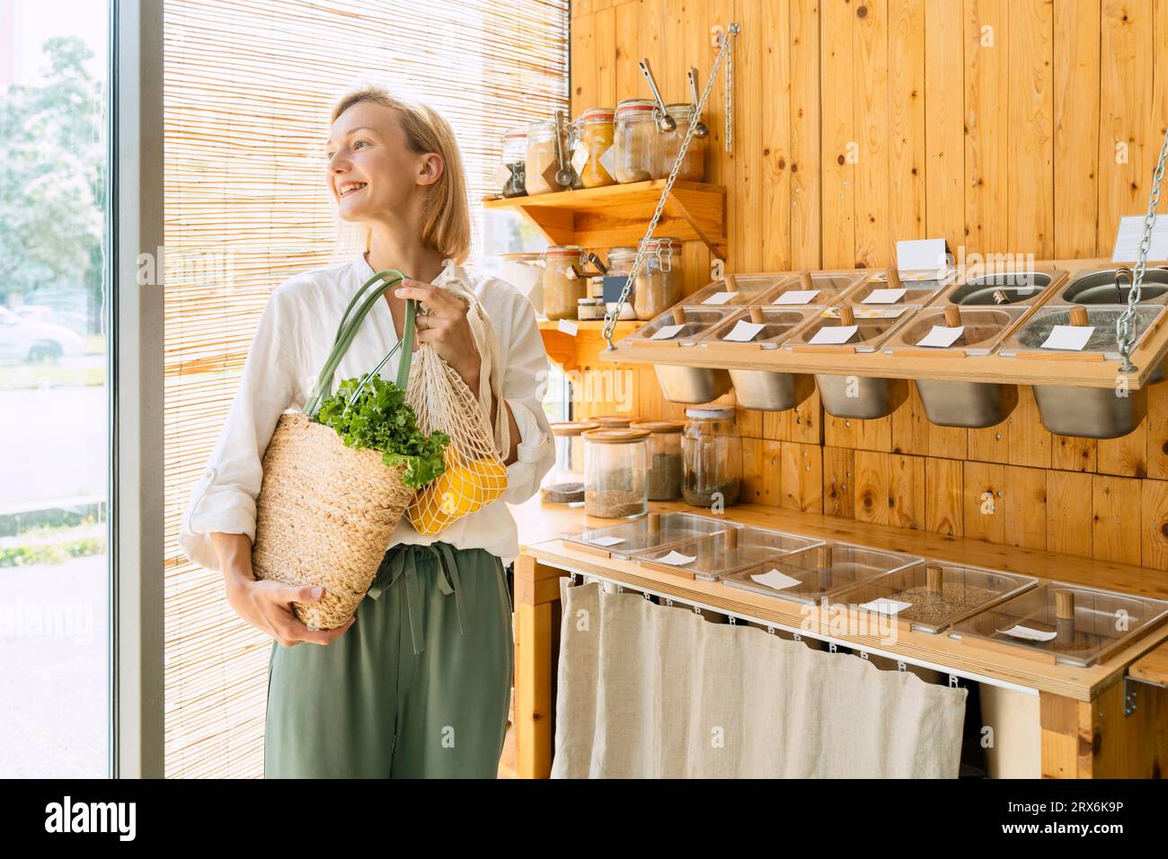 Happy woman with bag of groceries shopping at store Stock Photo