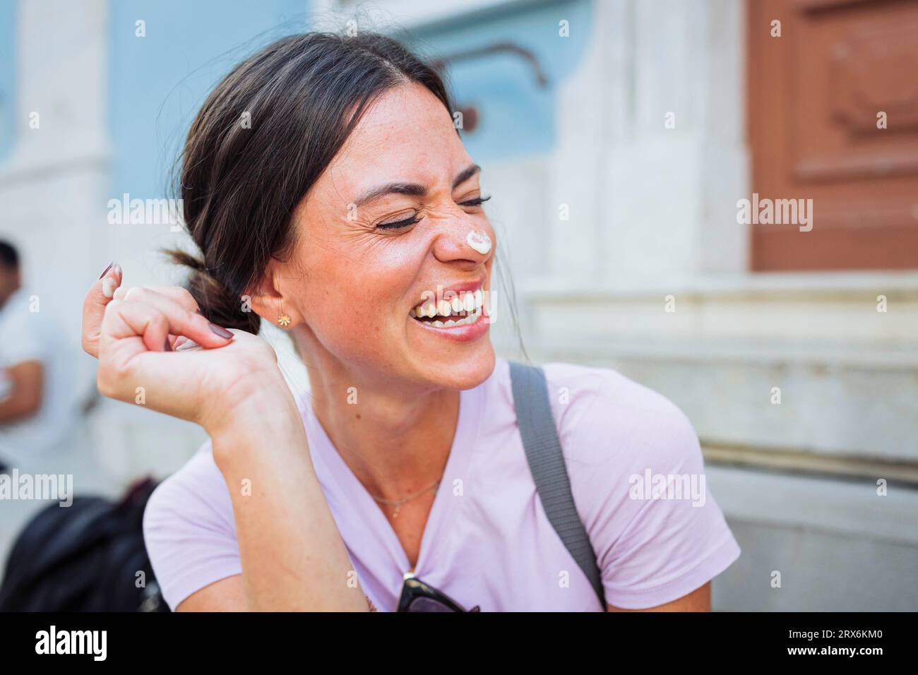 Cheerful woman laughing with ice cream on nose Stock Photo