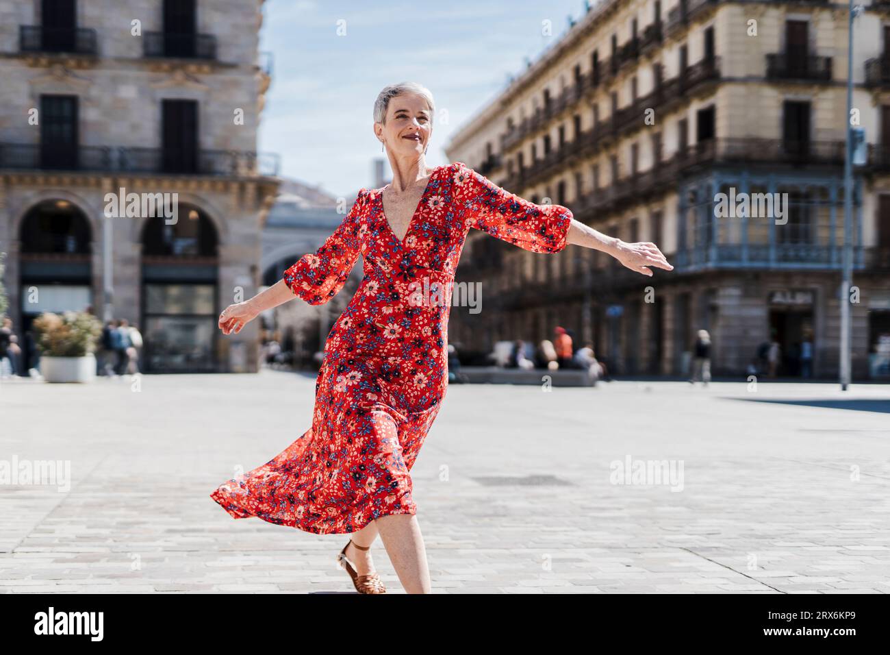 Happy woman wearing red dress dancing on street in city Stock Photo - Alamy