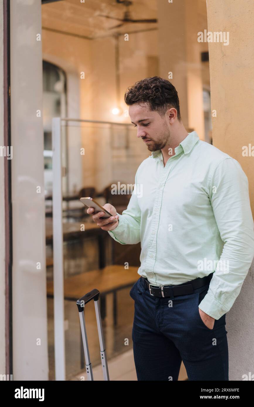 Young businessman using smart phone outside cafe Stock Photo