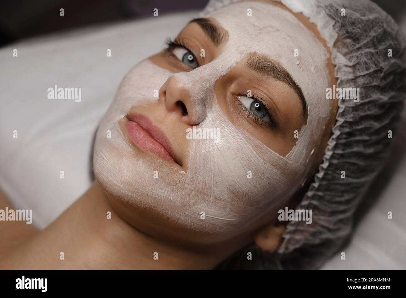 Smiling woman with skincare face mask in beauty salon Stock Photo